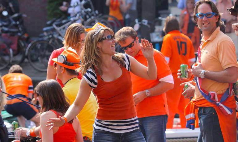 Buitenfeest met mensen in oranje gekleed.