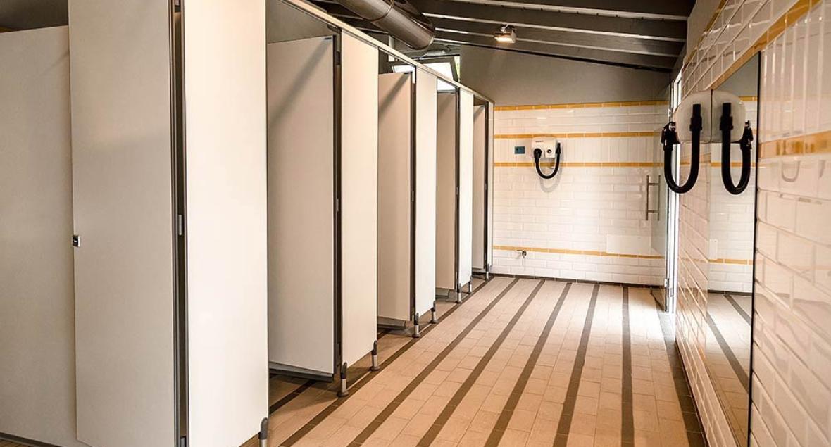 Moderne kleedkamer met douchehokjes en witte tegels.