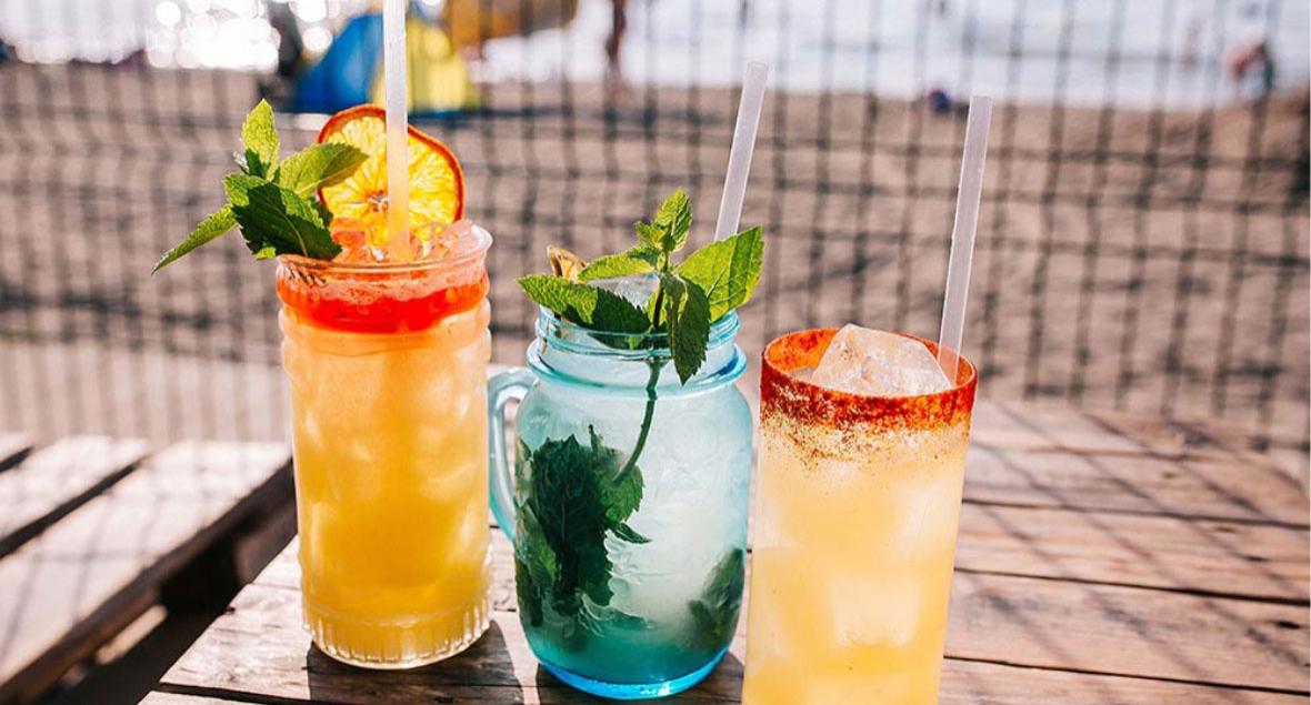 Three refreshing cocktails on the beach, perfect for summer.