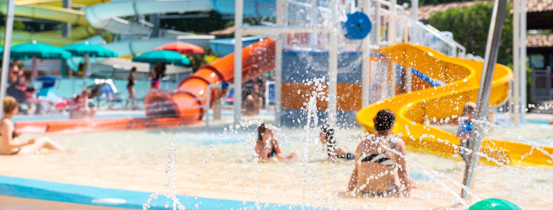 Wasserpark mit bunten Rutschen und Menschen, die das Schwimmbad genießen.