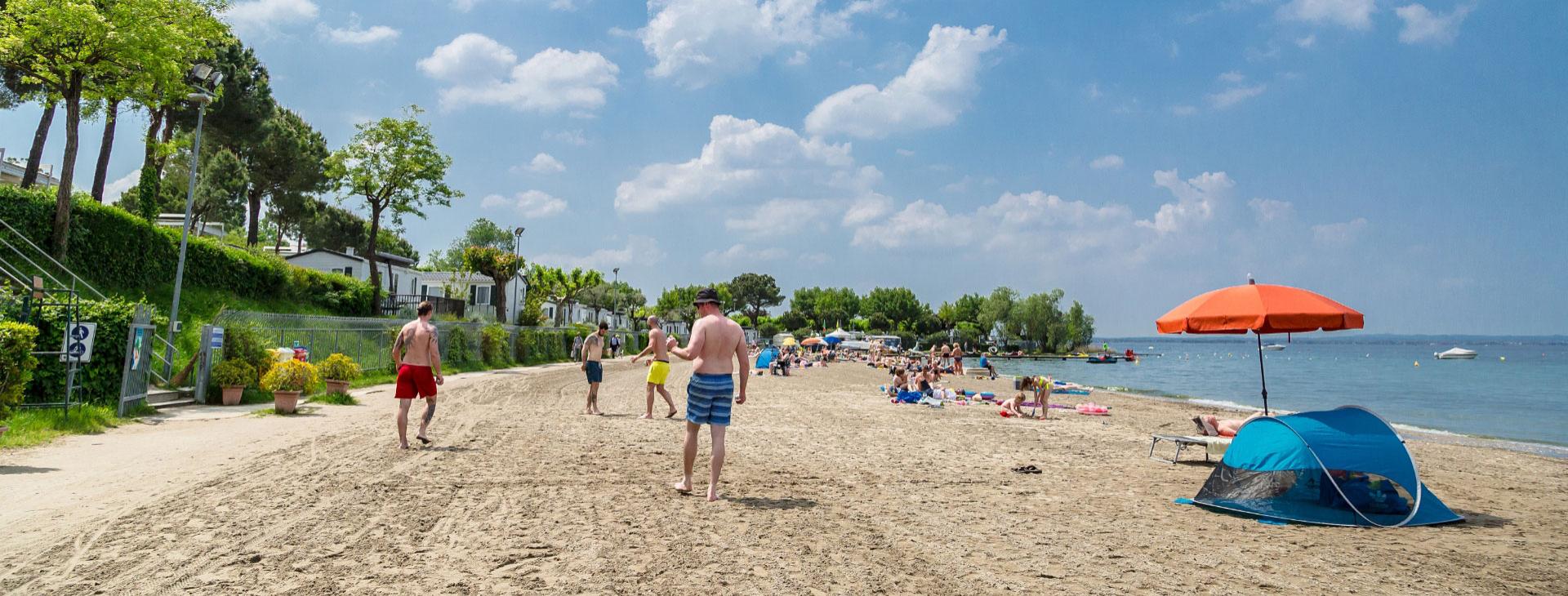 Sonniger Strand mit Menschen, die sich entspannen und spielen am Meer.