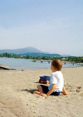 Kind speelt op het strand met een pier op de achtergrond.