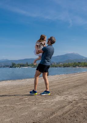 Menschen auf einem Pier, mit Booten im Hintergrund eines ruhigen Meeres.