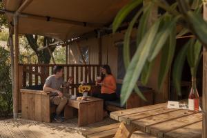 Paar frühstückt draußen auf einer Holzterrasse.