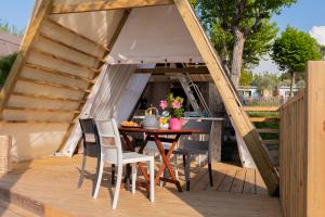 Gemütliche Holzterrasse mit Tisch, Blumen, umgeben von Natur.