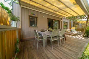 Terrazza accogliente con tavolo apparecchiato, sedie e sdraio sotto un pergolato.