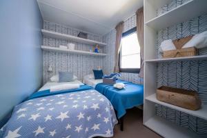 Gemütliches Zimmer mit Einzelbetten, blauen Decken und maritimer Dekoration.