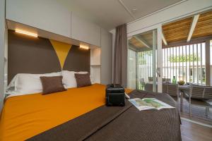 Camera moderna con letto accogliente, luce calda e vista su terrazza soleggiata.