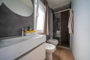 Bagno moderno, elegante, luminoso, con doccia, lavabo, bidet e asciugamani colorati.