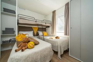 Camera accogliente con letti, peluche e luce calda.