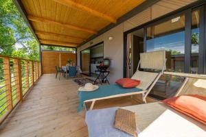 Terrazza accogliente in legno, sdraio, cuscini colorati, atmosfera rilassante e natura verde.