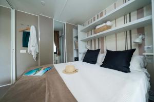 Gezellige kamer met bed, zwarte kussens en strohoed.