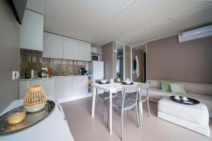 Lichte, moderne woonkamer met keuken, eettafel en knusse bank.