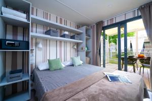 Camera accogliente con letto, decorazioni moderne e vista su terrazza soleggiata.