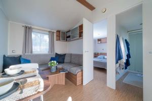 Accogliente soggiorno con divano, tavolo apparecchiato e camera da letto luminosa.
