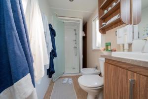 Bagno accogliente con doccia, accappatoi colorati e dettagli in legno.
