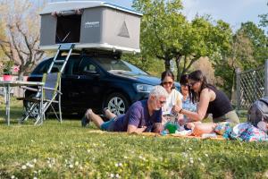 Glückliche Familie beim Camping, Sonne scheint, üppige Natur, geteilte freudige Momente.