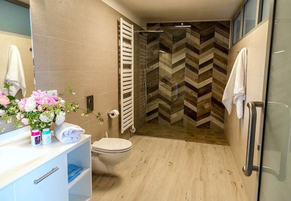 Moderne badkamer met douche, bloemen en witte handdoeken.
