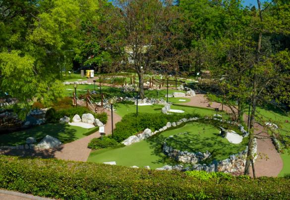 Folk spiller minigolf i en udendørs park.