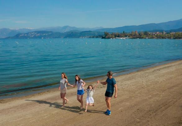 Sonniger Strand mit Menschen, die sich unter den Bäumen entspannen.