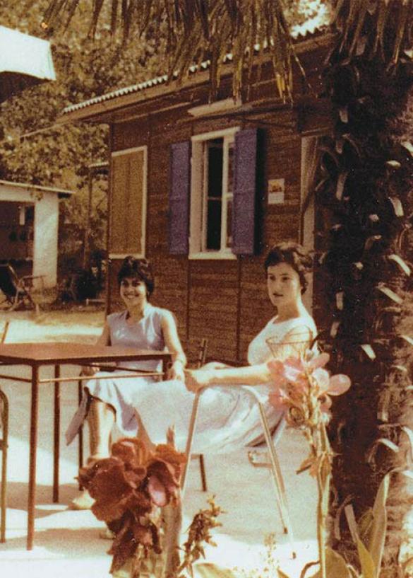 Drie vrouwen zitten aan een buitentafel onder parasols.