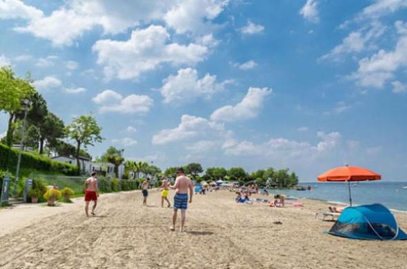Spiaggia soleggiata con persone che si rilassano e nuvole nel cielo.