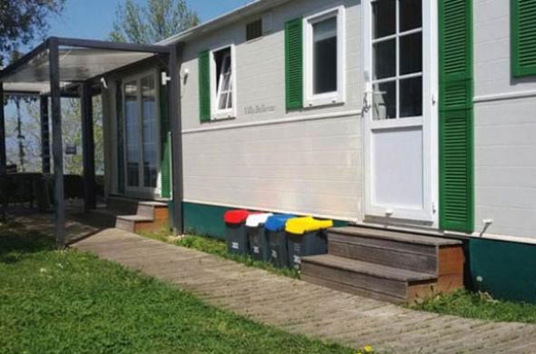 Casa mobile con bidoni colorati per la raccolta differenziata.